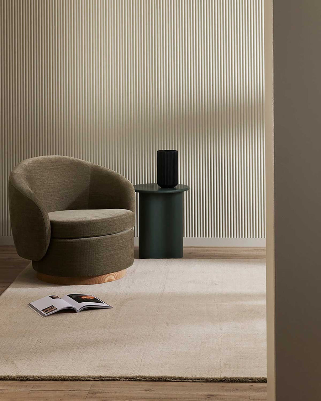 A reading nook with a neutral wool floor rug in a soft beige tone.