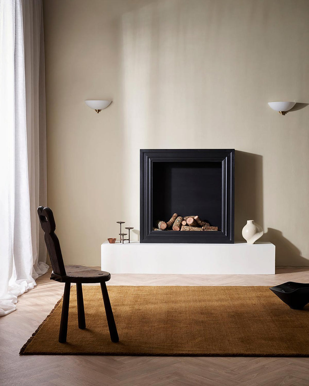 A rich warm brown 100% wool floor rug in front of a cosy looking fireplace.