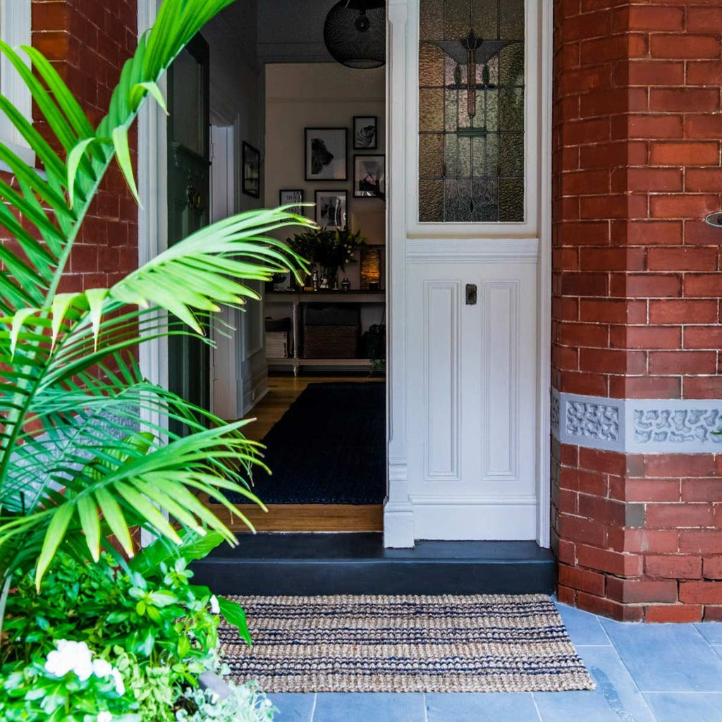 An entrance way with a black and natural brown handmade jute entrance mat.