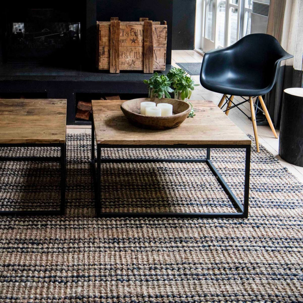 A chic modern living area with a hand knotted black and brown striped floor rug made of durable jute.