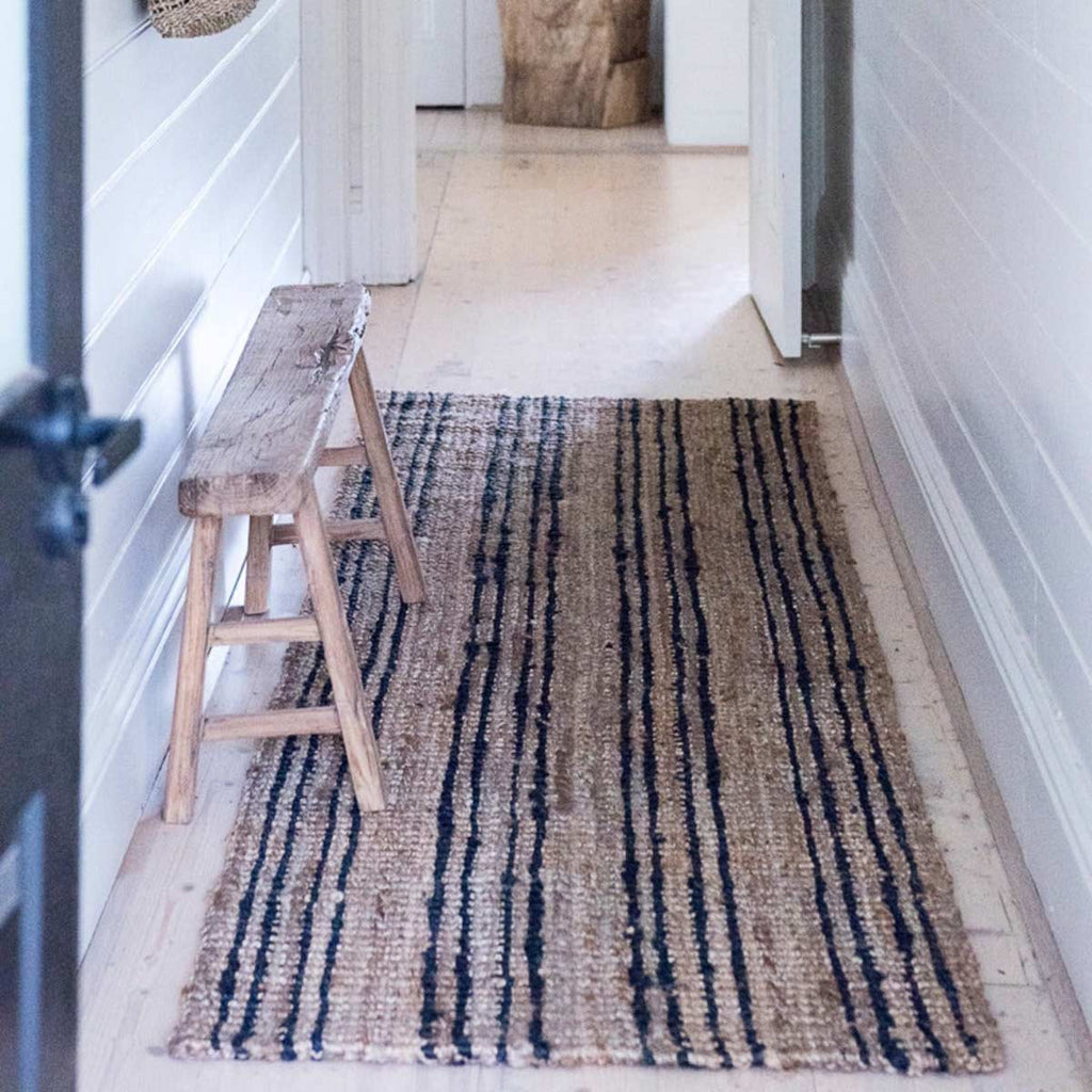 A hallway space with a small runner in black and natural brown jute with stripes.