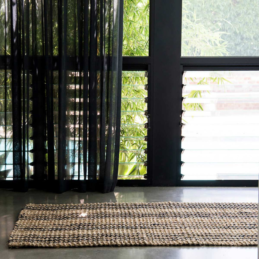 An entrance way with a jute runner in striped natural brown and black.