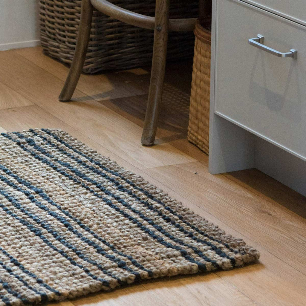 A floor mat with black and brown stripes, made of natural jute fibres.