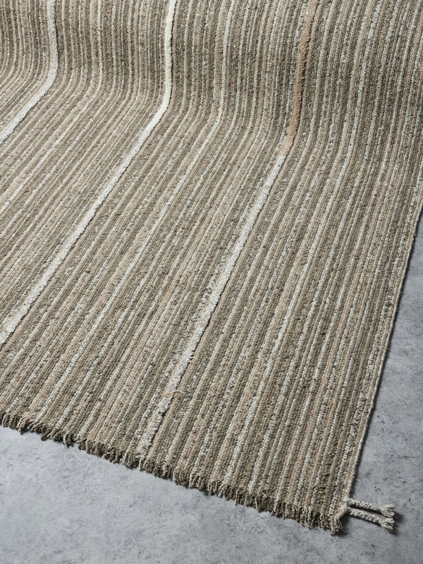 A funky striped rug in olive and muted brown shades, with a braided and fringed edge. Handmade with 100% NZ wool by Tribe Home