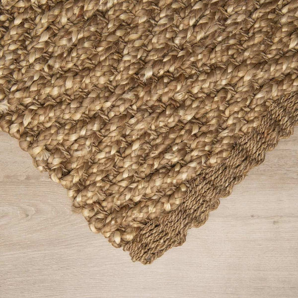 A corner view of a textural boucle weave patterned jute floor rug.