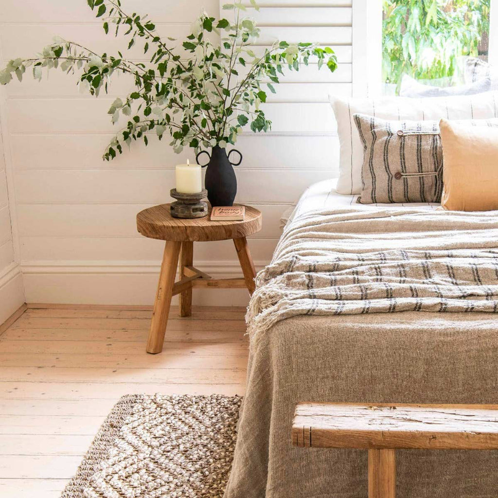 A cosy bedroom in neutral tones with a patterned jute floor rug in natural brown.