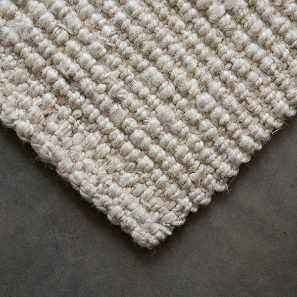 A corner of a white washed jute floor rug.
