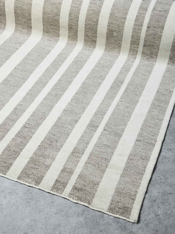 A striped taupe and ivory floor rug,  handloomed with 100% NZ wool by Tribe Home