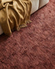 Weave Home wool throw blanket in colour 'camel' - a light brown, next to a red-toned Weave Almonte floor rug