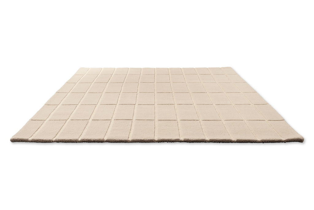 A Marimekko grid patterned rug in NZ wool and in a neutral creamy white, seen in perspective