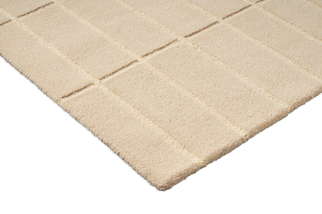 Corner close up of a  Marimekko grid patterned rug in NZ wool and in a neutral creamy white