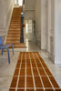 A Marimekko NZ wool rust patterned rug features in an elegant hallway