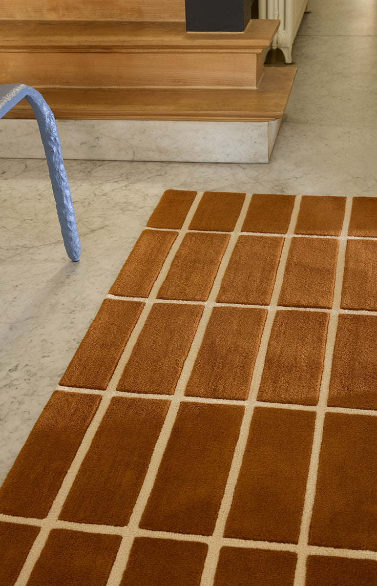 Mid shot of a  Marimekko NZ wool grid patterned rug in a beautiful rust toned colour