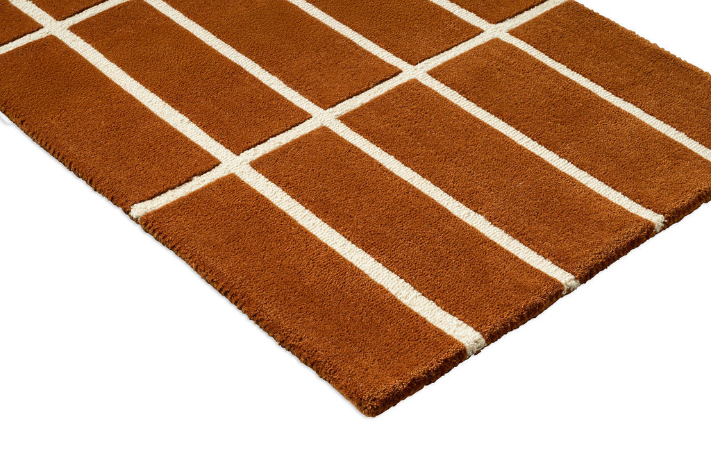 Corner close up of a Marimekko NZ wool geometric patterned rug in an on-trend rusty brown