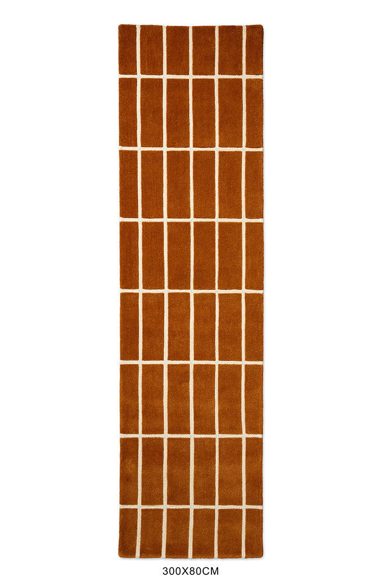 A Marimekko NZ wool geometric patterned rug in a rusty brown, seen from above