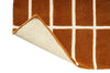 Close-up of a brown and beige checkered rug corner