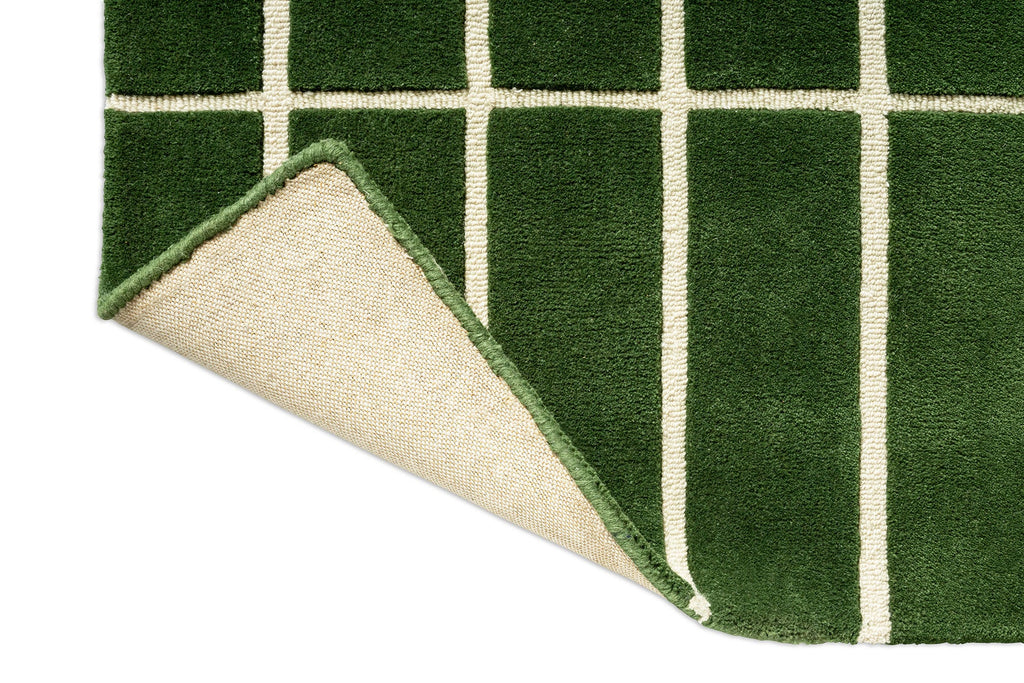 Close up corner view of a green geometric Marimekko NZ wool rug  with corner folded up