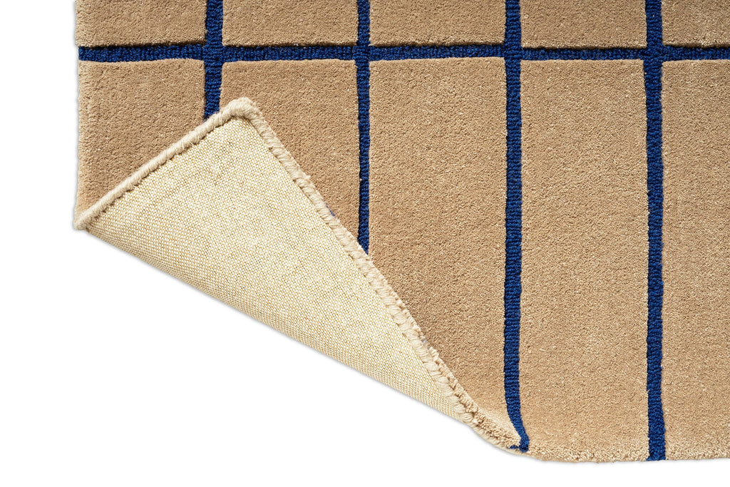 Close up of a Marimekko NZ wool runner rug with blue grid pattern on a beige  background with corner folded up