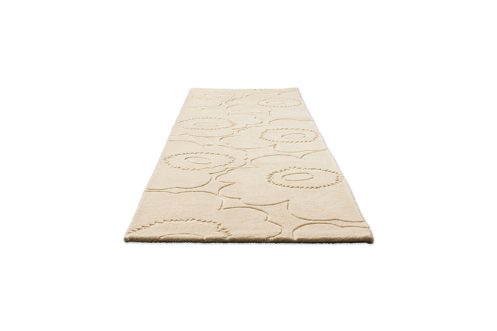 Perspective view of a Marimekko runner rug in a creamy white with the iconic unikko floral design cut into it