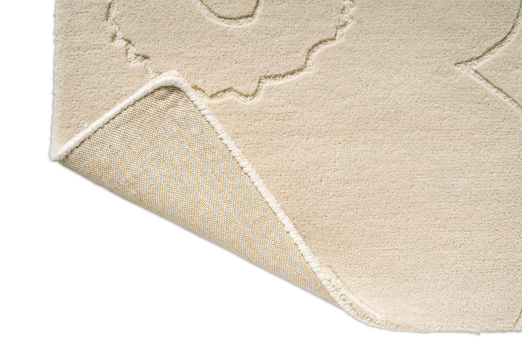 Corner close up of a creamy white Marimekko NZ wool rug with a subtle floral unikko graphic and backing