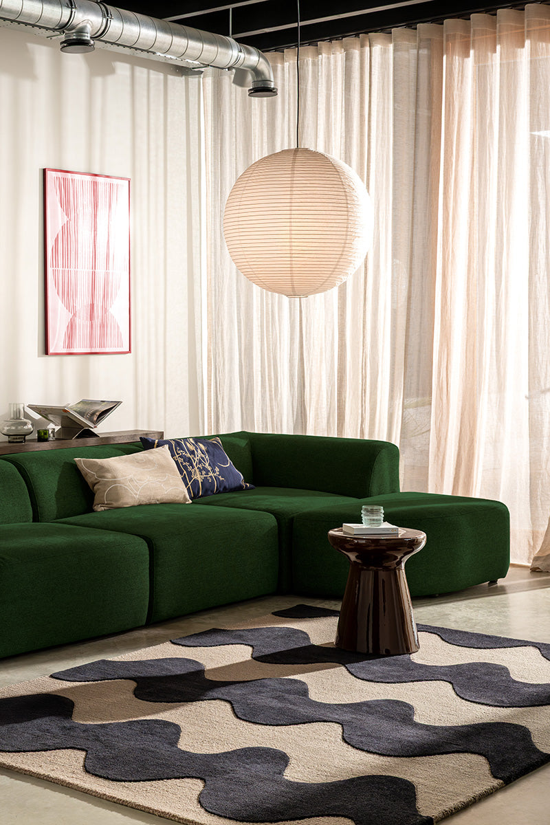 Modern living room with a green sofa, abstract art, and a Marimekko NZ wool Rug with black wavy pattern 