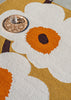 Marimekko Unikko floral-patterned outdoor rug with white flowers and orange centers on a mustard background