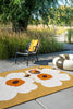 Outdoor setting with a chair, and Marimekko outdoor rug featuring the iconic Unikko floral design in white and orange