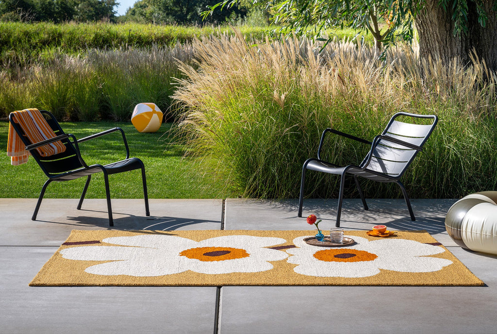 Outdoor setting featuring an outdoor rug featuring the iconic Marimekko Unikko floral design in orange and white