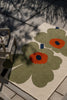 Marimekko Unikko floral-patterned outdoor rug on a patio with a wooden chair.