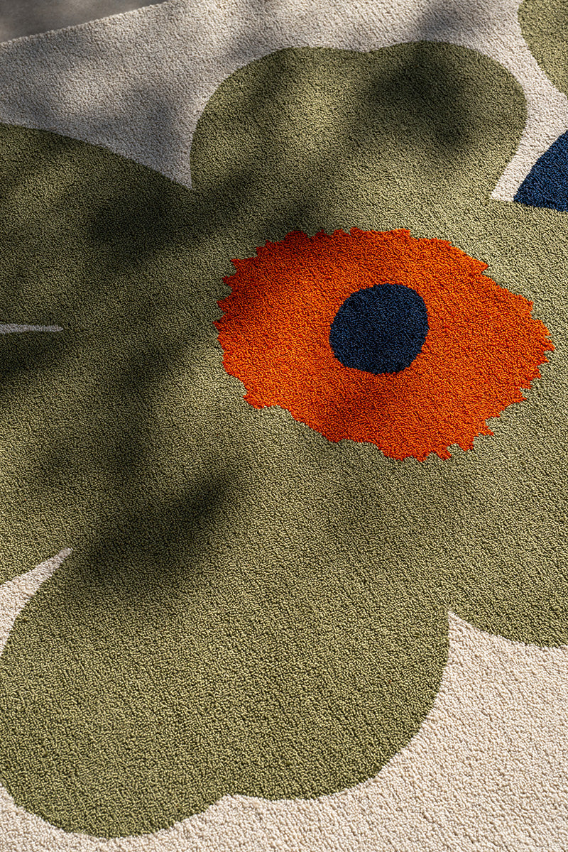 Close-up of a Marimekko outdoor rug with a floral pattern featuring green leaves and an orange flower.