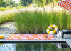 Outdoor setting with a pool featuring a Marimekko Unikko pink and orange outdoor rug
