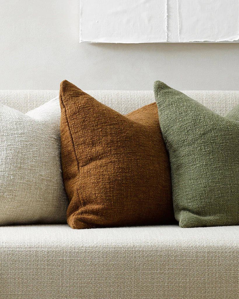 Three natural toned Baya cyprian cushions on a boucle couch