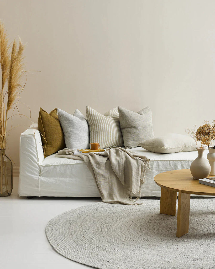 A contempory living room with a white couch and five stunning contrast linen cushions