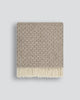 Patterned wool blanket with fringe on a light gray background