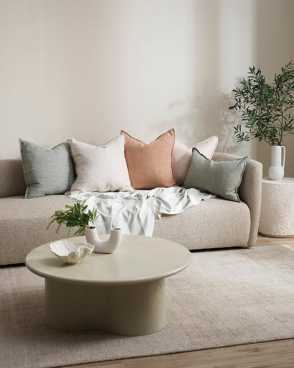 Baya square linen cushion in colour sage green, shown with other cushions in a contemporary living room