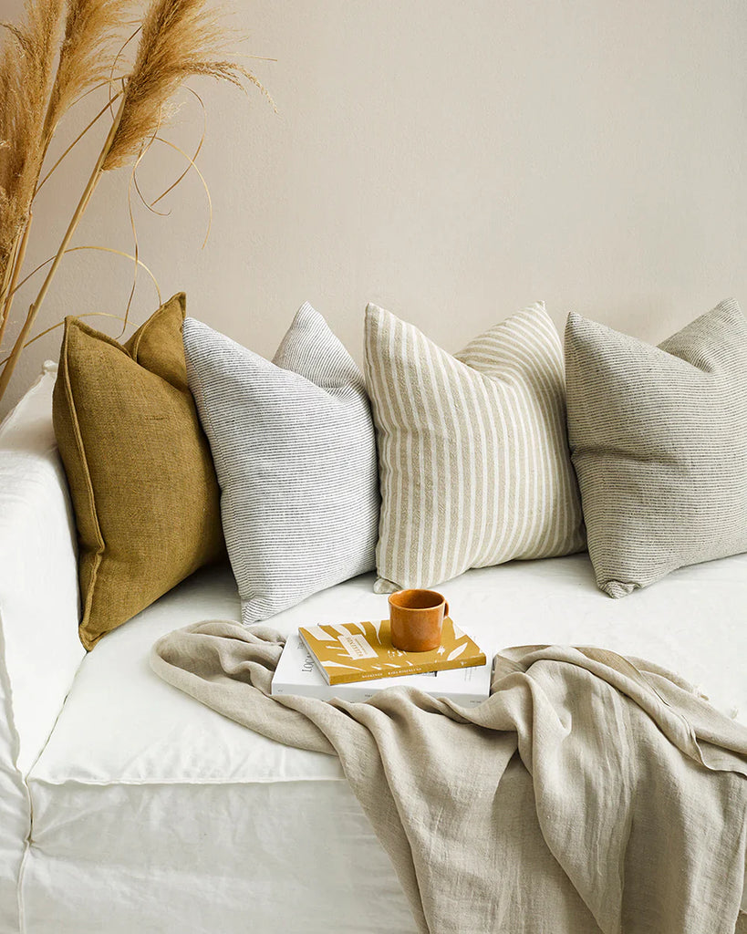 Four beautiful designer cushions in warm tones, on a modern couch