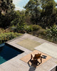 Voew from above of the three Baya Lonsdale outdoor rugs, on a deck beside a pool.