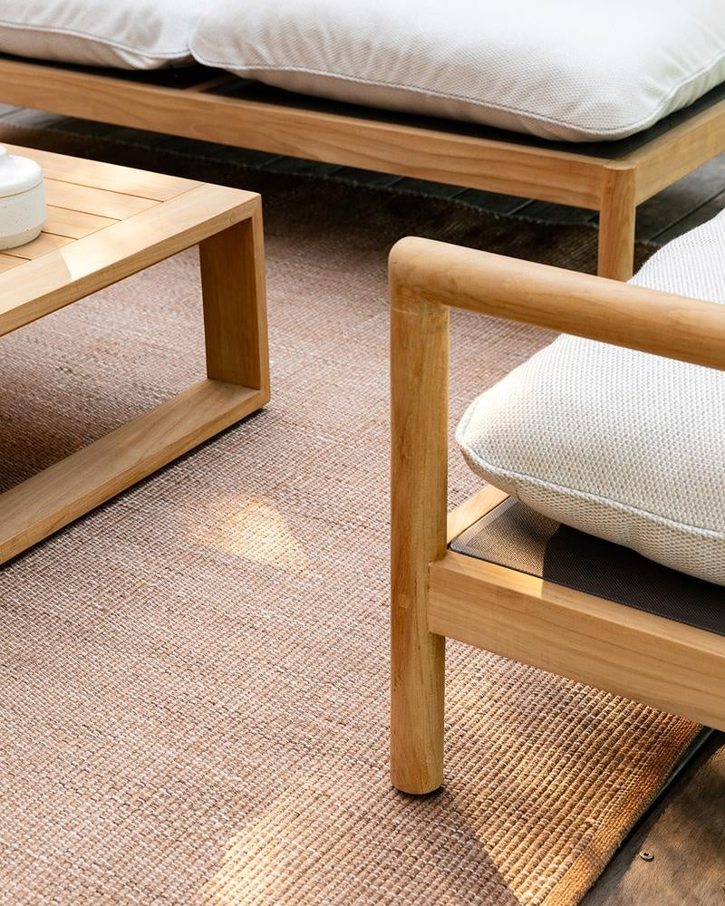 Close up of a stylish brown, woven outdoor rug by Baya, seen under wooden outdoor furniture