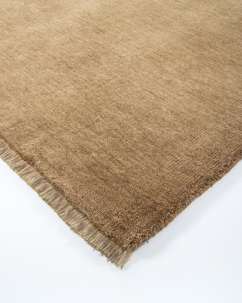 The Baya Sandringham light-mid brown 'Fenugreek' wool rug, seen close up at the corner highlighting the fringe detail