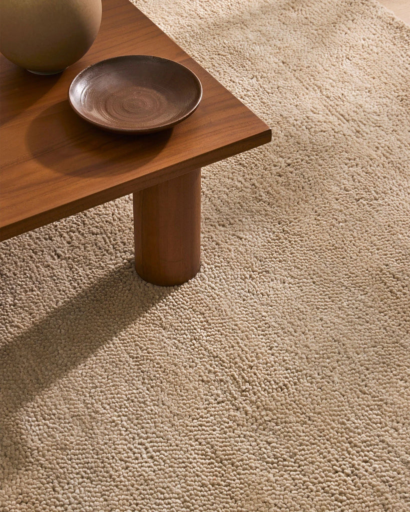 A soft, milky-brown coloured wool rug with a thick, plush pile - the Valencia Dune by Weave Home - seen under a coffee table.