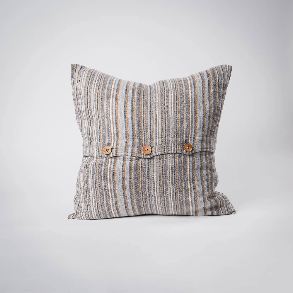 A front on view of a cushion with stripes in muted colours of ochre, slate, and red. The front is closed with three wooden feature buttons. 