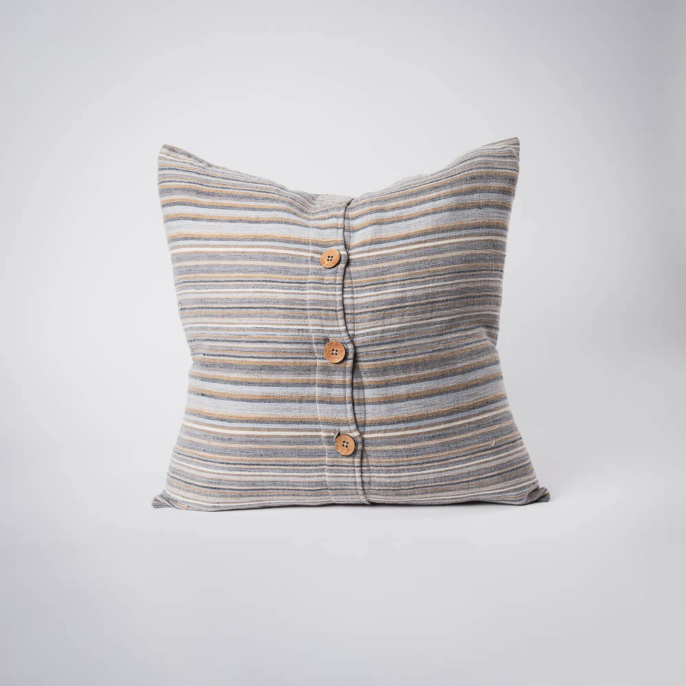 A front on view of a cushion with stripes in muted colours of ochre, slate, and red. The front is closed with three wooden feature buttons. 