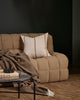 Beige sofa with a striped neutral cushion, wool throw and brown rug