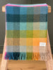 A vibrant, colourful NZ wool throw blanket by Exquisite Wool Traders, hanging folded