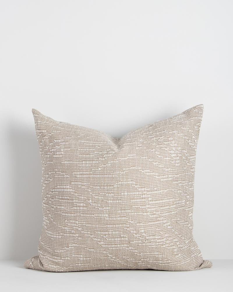 A beautiful beige designer cushion by Baya NZ, seen against a white background.