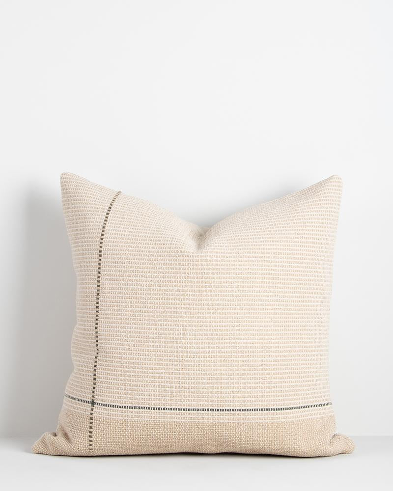 Cream and beige linen and cotton cushion with a green linear detail, seen in full against a white background.