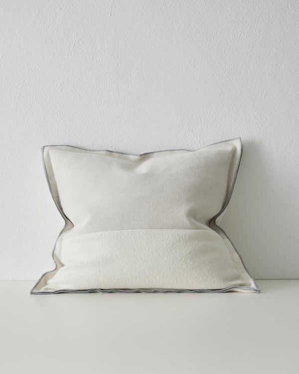 A two-toned modern cushion with double flange edge, in a pale beige and ivory - the Riccardo Glacier by Weave Home.