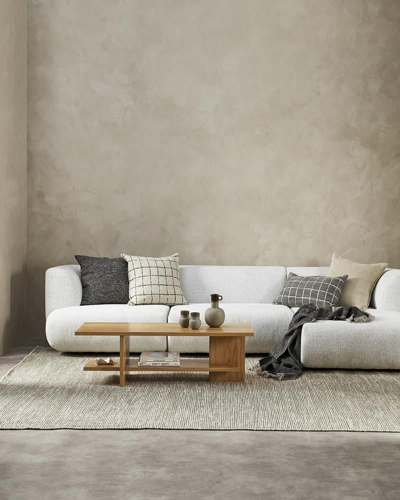 Complementary designer cushions by Baya in natural linen colours and black, styled on a white couch in a modern NZ living room.