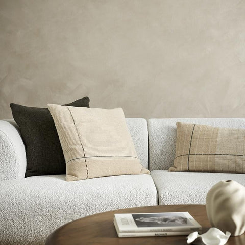 A couch styled with cushions in beige, taupe, cream and camel tones, with highlights of forest green by Baya.