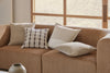 Close up of four Weave Home neutral cushions, on a warm-toned brown couch, that pair well together.